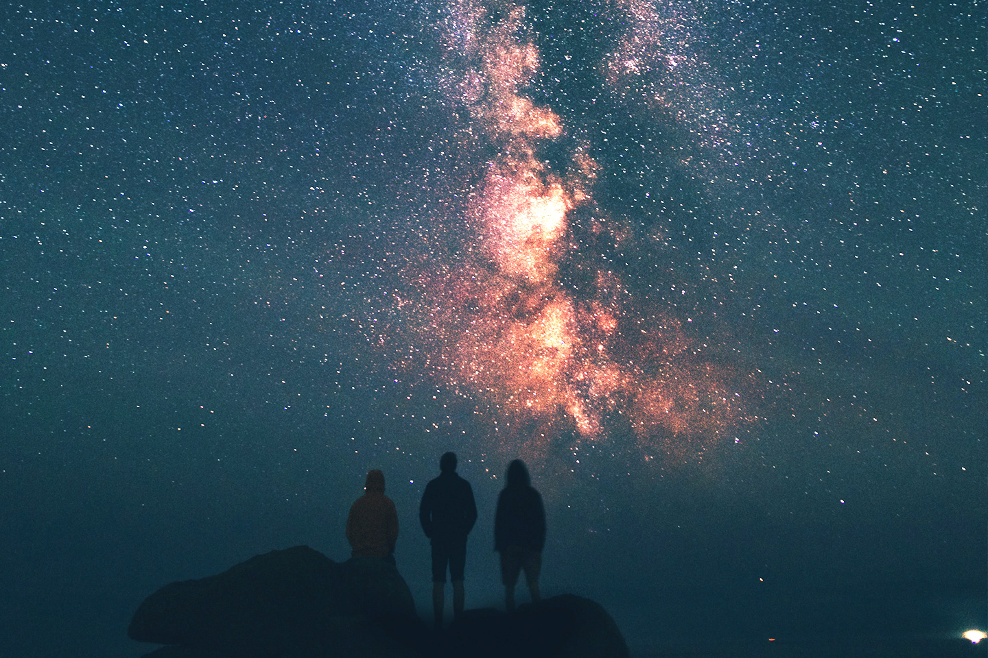Three people's silhouettes watching the night sky